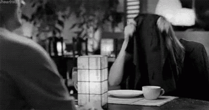 a black and white photo of a man and a woman sitting at a table .