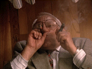 a man with glasses is smoking a pipe in a room