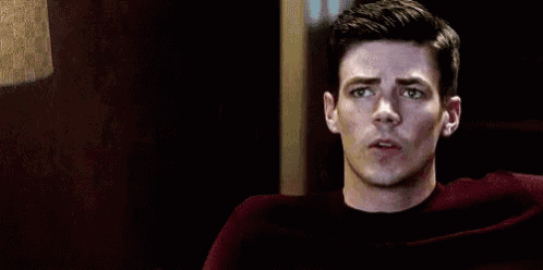a man in a red shirt is sitting in a chair and looking at something .