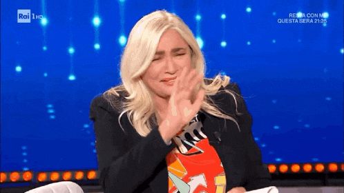 a woman claps her hands while sitting on a chair on a television show