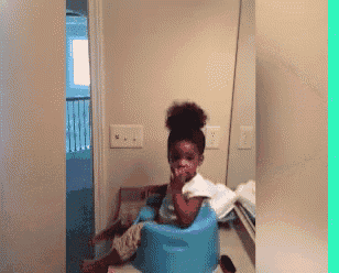a little girl is sitting in a blue chair eating a napkin