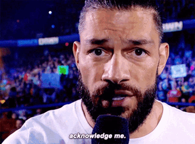 a man with a beard speaking into a microphone with the words acknowledge me