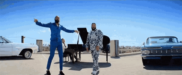 a man in a blue suit stands next to a piano