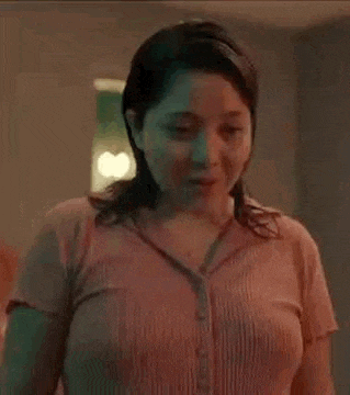 a woman in a pink shirt is standing in a room and looking at something .