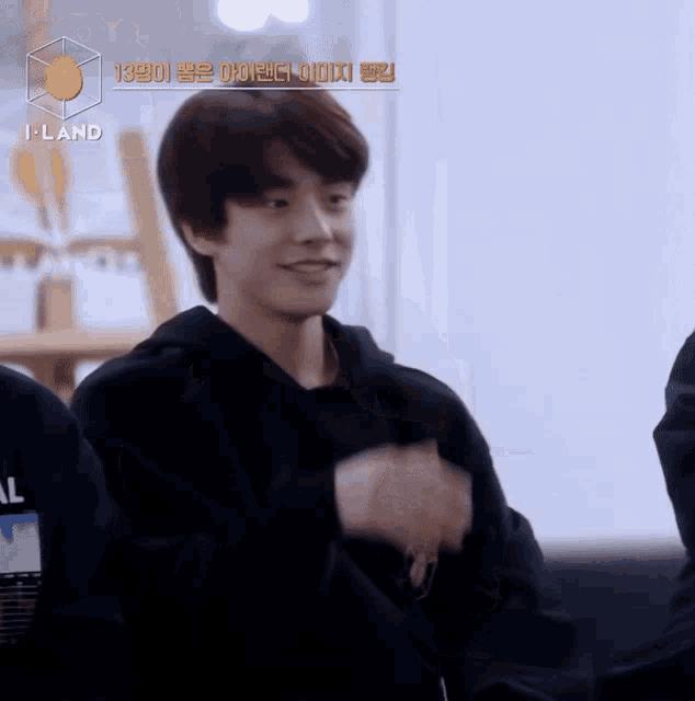 a young man in a black hoodie with i-land written on the bottom