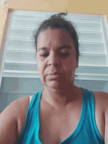 a woman in a blue tank top takes a picture of herself