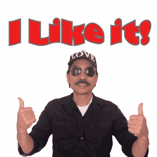 a man wearing sunglasses and a hat that says love gives two thumbs up in front of a sign that says i like it