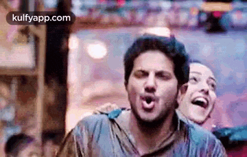 a man and a woman are standing next to each other and laughing in a crowd .