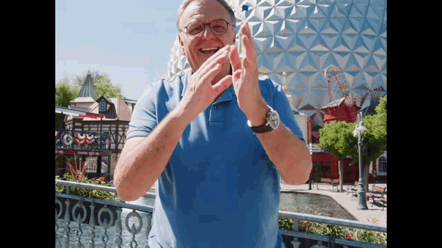 a man wearing glasses and a blue shirt is clapping