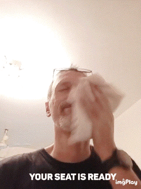 a man wipes his nose with a napkin and the words " your seat is ready " below him