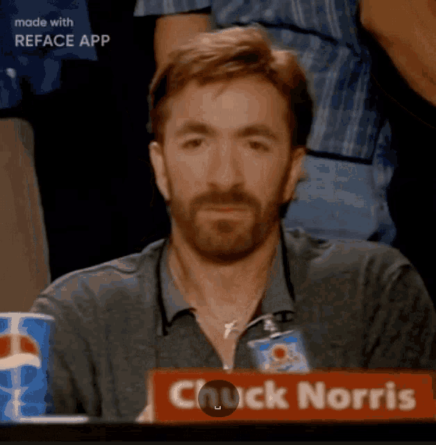 a man with a beard sits at a table with a pepsi can in front of him