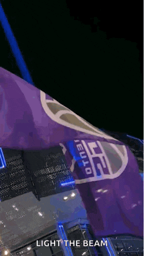 a purple flag with the words light the beam on it is flying in the air