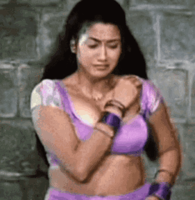 a woman in a purple bra is standing in front of a wall .