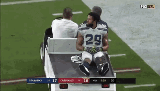 a football player with the number 29 on his jersey is sitting on a cart on the field .