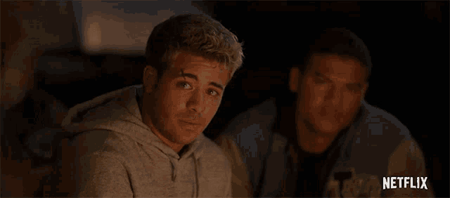 two men are sitting next to each other with a netflix logo in the background