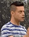 a man in a blue and white striped shirt is standing in front of a tree .