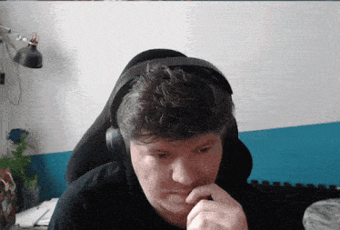 a man wearing headphones sits in front of a blue and white wall