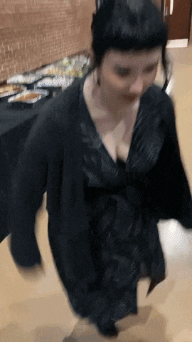 a woman in a black dress is dancing on a wooden floor in a room .