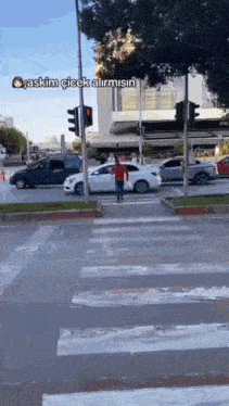 a man in a red shirt is crossing the street in front of a red traffic light ..