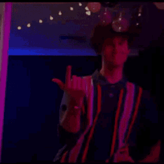 a man in a striped shirt stands in a dark room