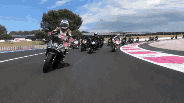 a group of people are riding motorcycles down a track