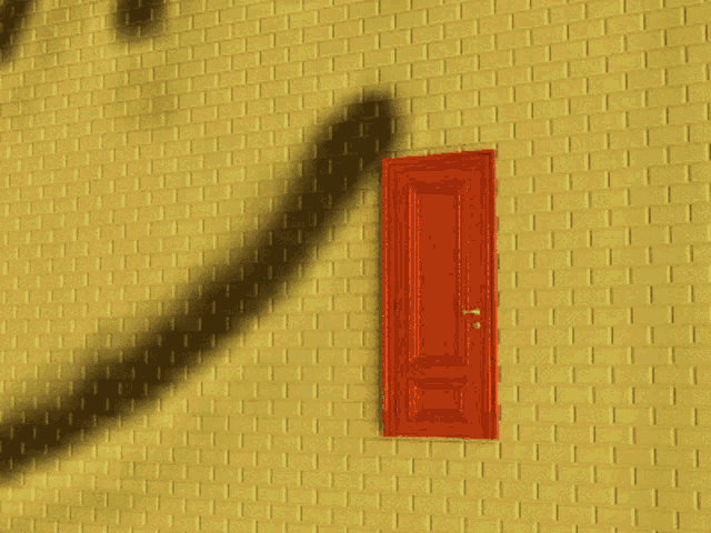 a yellow brick wall with a red door that has a drawing of a face on it