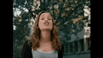 a woman with long hair is making a funny face in front of a tree .
