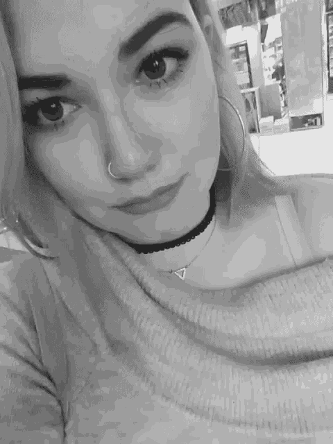 a woman with a nose ring is wearing a choker and hoop earrings