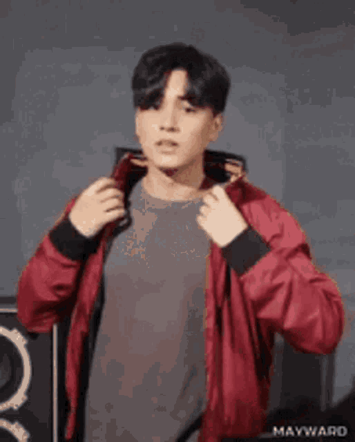 a man wearing a red jacket is adjusting his hood