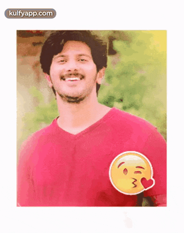 a man wearing a red shirt with a kissing smiley face on it