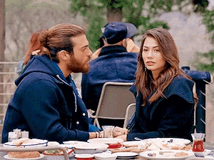 a man and a woman are sitting at a table holding hands and looking at each other