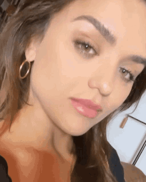a close up of a woman 's face wearing hoop earrings and a black shirt .