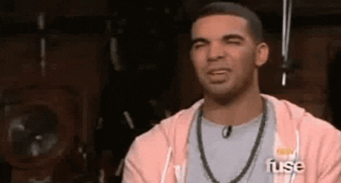a man wearing a pink hoodie and a necklace is making a face .