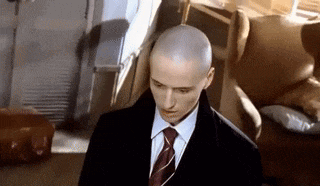 a bald man in a suit and tie looks down
