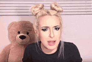 a woman with two buns is sitting next to a teddy bear .