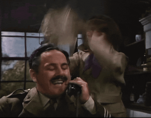 a man with a mustache is talking on a telephone
