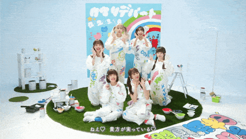 a group of girls are sitting in front of a sign that says ' oi ' on it