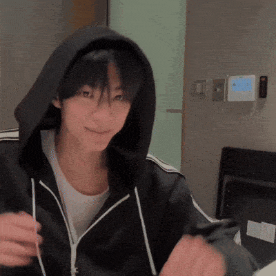 a young man wearing a black hoodie and a white shirt is smiling