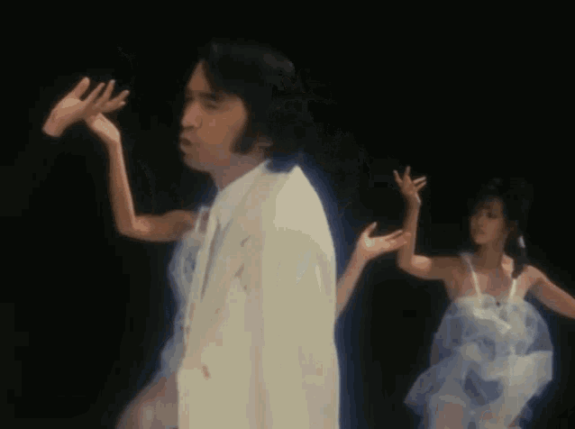 a man in a white suit is standing in front of two women in white dresses