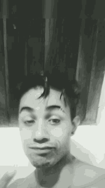 a black and white photo of a shirtless man making a face