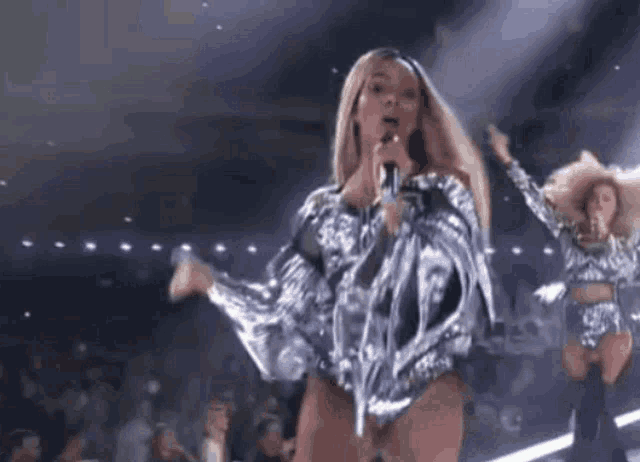 a woman is singing into a microphone on a stage while dancing .
