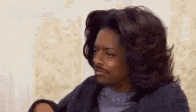 a man with long hair and a mustache is making a funny face while sitting on a couch .