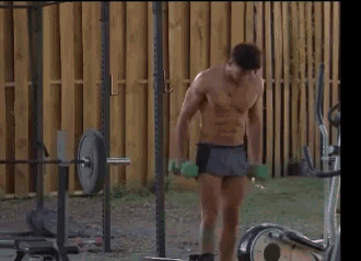 a shirtless man is lifting dumbbells in a gym .