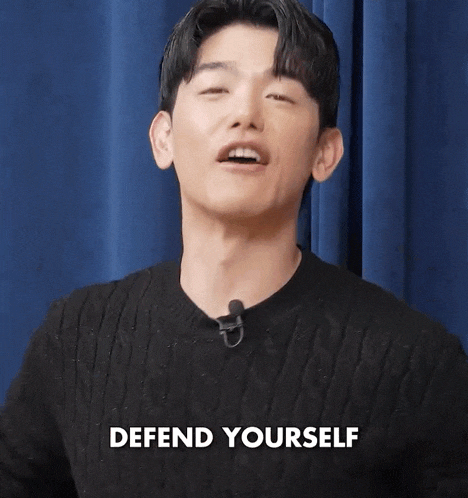 a man is wearing a black sweater and a microphone and says defend yourself