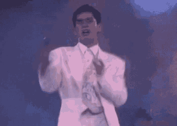 a man in a white suit is dancing on a stage with his arms outstretched .