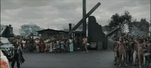 a group of people standing in front of a telephone booth with a cross in the background