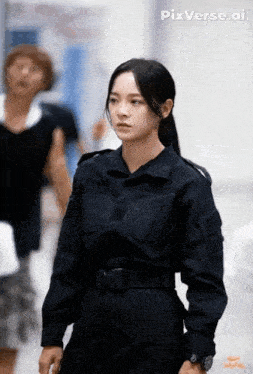 a woman in a black uniform is standing in a hallway looking at the camera .