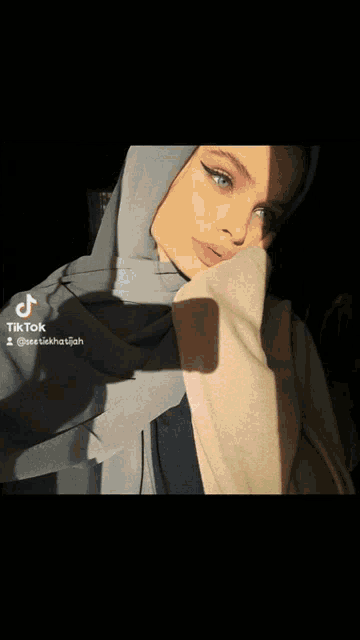 a woman wearing a hijab is taking a selfie with a tik tok watermark