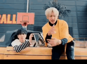 a man in a yellow sweater is sitting in a car next to another man in a striped shirt .