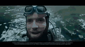 a man wearing a helmet and goggles is swimming in the ocean .